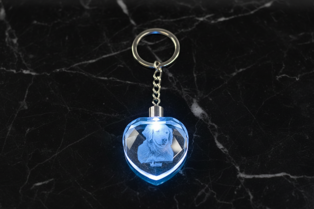 Heart-shaped keychain with a blue light on a dark marble surface